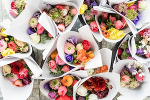Overhead view of bunches of colourful ranunculus wrapped in white paper