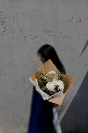 Person holding a sympathy bouquet of flowers wrapped in brown paper in Vancouver