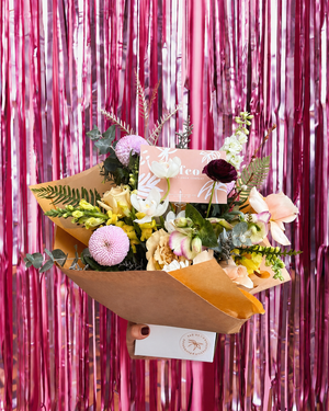 Bouquet of flowers with a card against a pink tinsel background